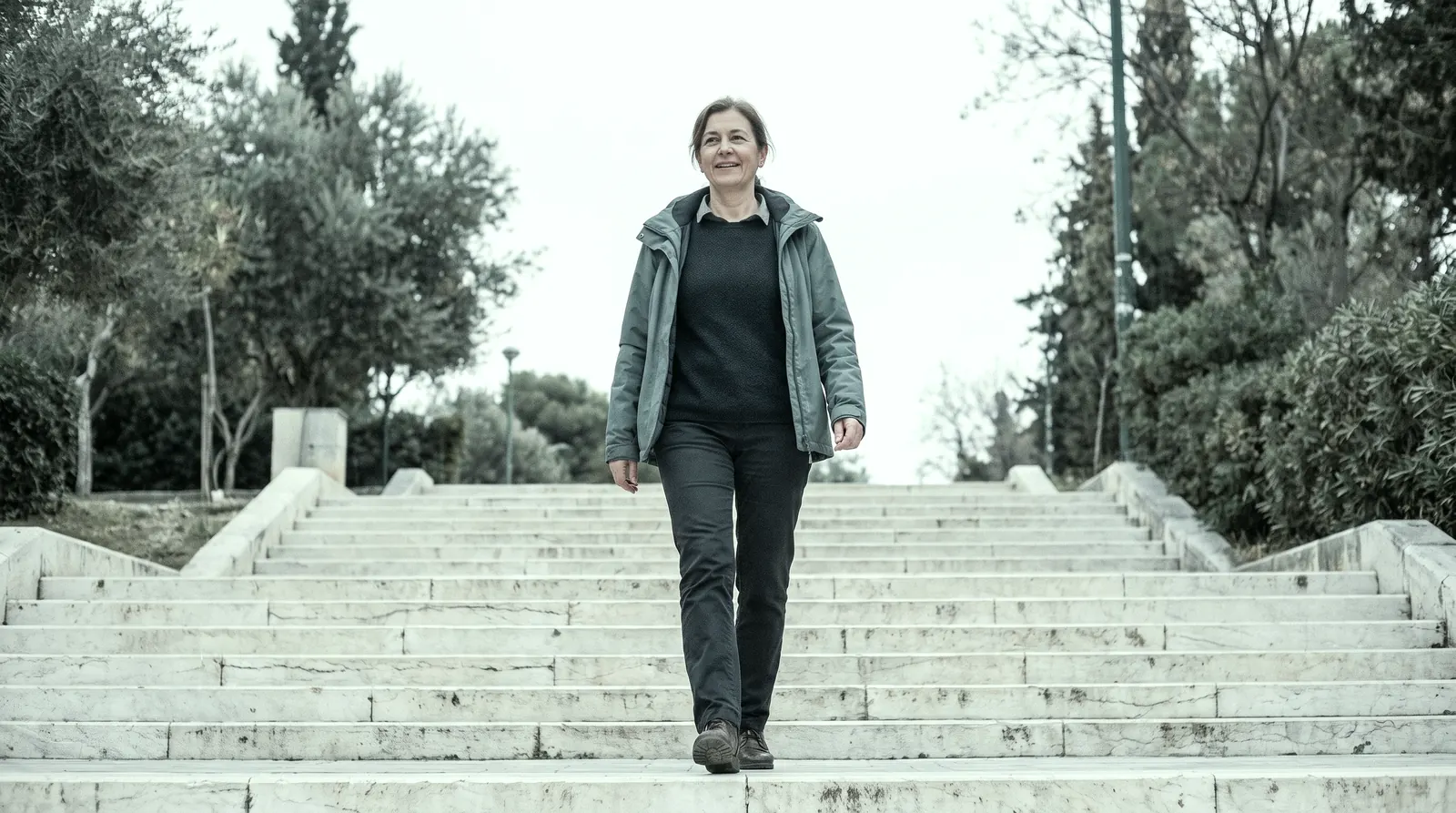 Frau geht entspannt eine Treppe im Park hinauf